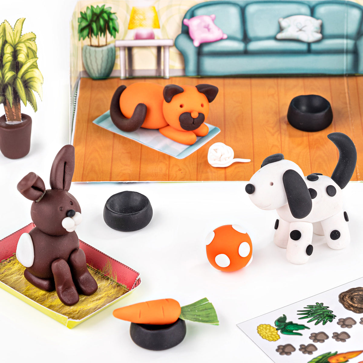 Set of clay animal figures including a rabbit, dog, and cat on a table with a toy couch in the background.