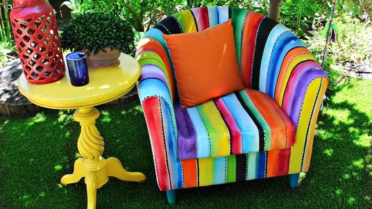 Colorful striped armchair with a bright orange pillow on a grassy area