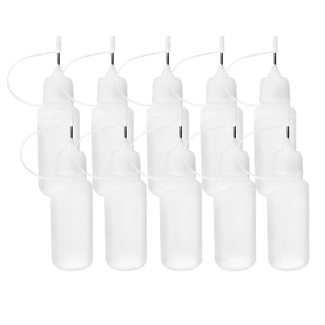 Ten small translucent white squeeze bottles with metal tips for fine application of paint on a white background