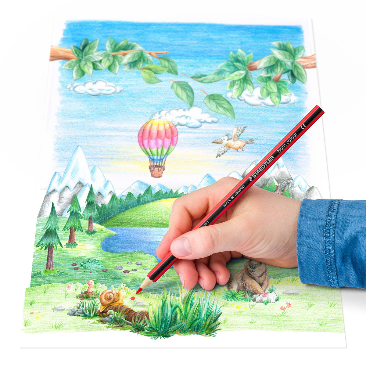 Coloring book with a hand holding a red pencil, depicting a colorful landscape with trees, a hot air balloon, and animals.