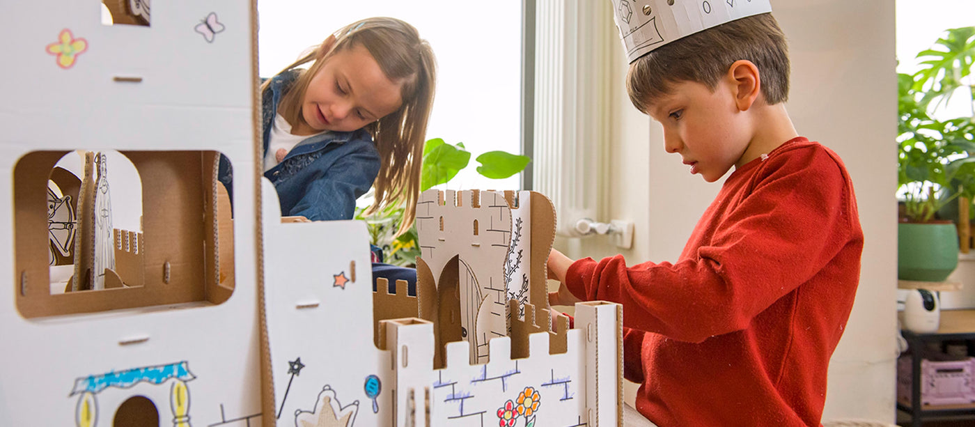 Two children playing with a 3d puzzle cardboard castle set indoors.