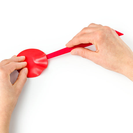 fimp polymerclay tool lifting a rolled piece of fimo off a white surface