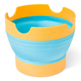 A collapsible silicone bowl by Staedtler, featuring a bright blue interior and orange-yellow outer rim and base, shown on a clean white background.