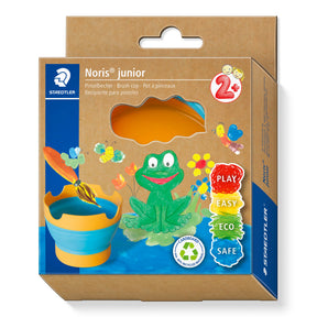 Noris Junior brush cup set in its original retail packaging by Stedtlr. The box is brown cardboard with blue side panels and colorful illustrations of a green frog, a blue and yellow cup, and a gold paintbrush.