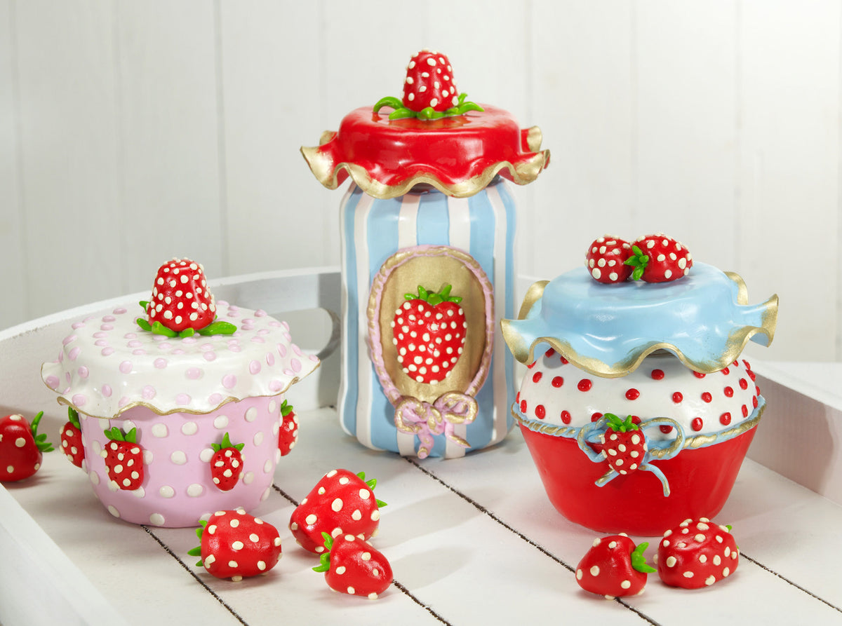 Three decorative fimo polymer clay  strawberry-themed jars styled like cupcakes, arranged on a white wooden surface against a white paneled background.