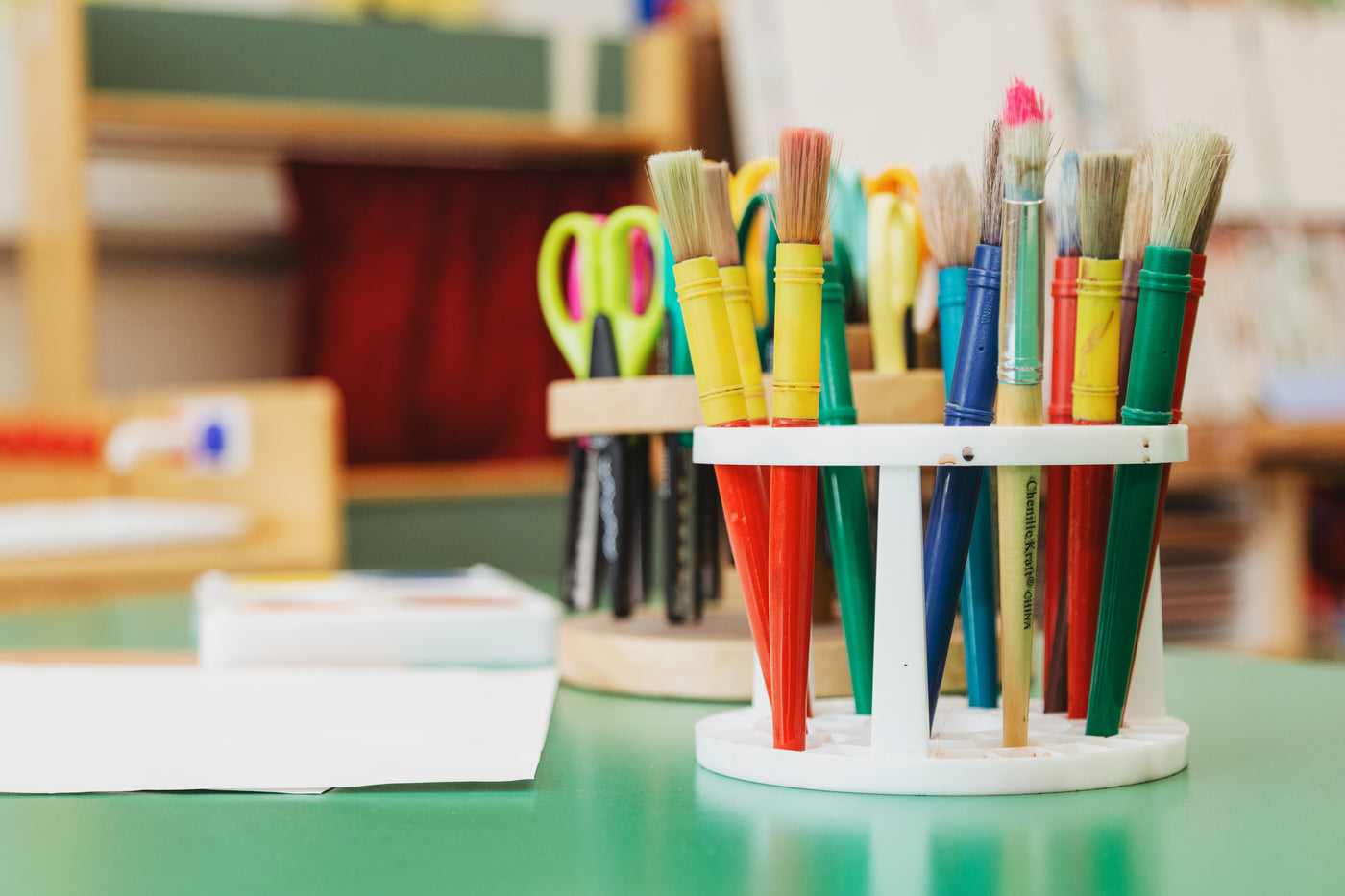 some paintbrushes and scissors standing upright on a crafters worktop