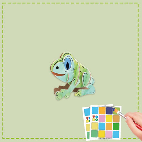 Colorful frog toy with color swatches and a brush on a green background
